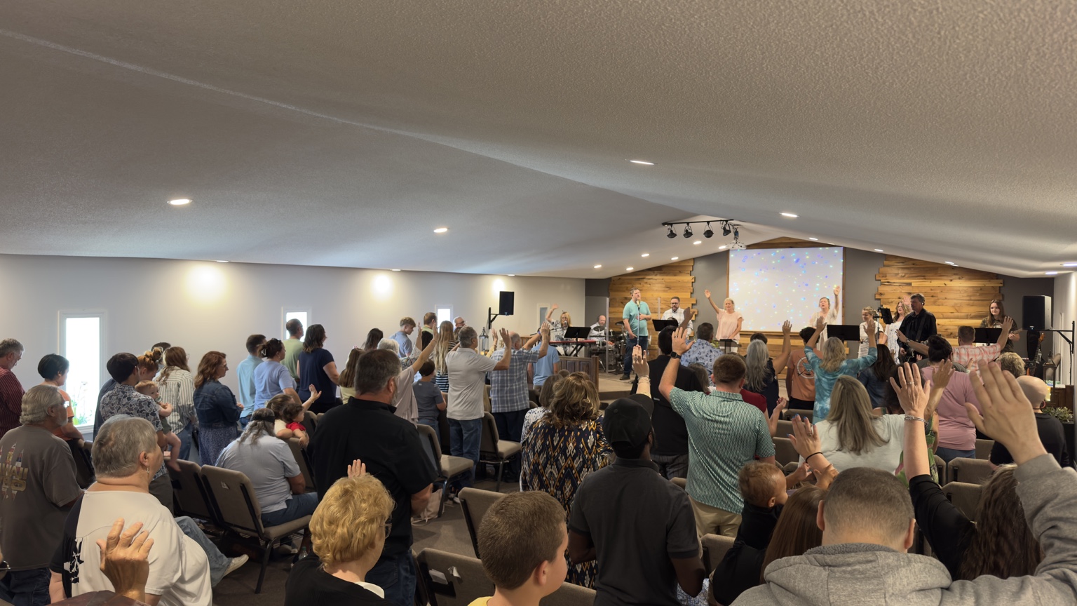 New Vision congregation with hands raised in worship and the worship team leading onstage
